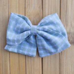 Lazo infantil de tela vichy verde con cuadros blancos sobre fondo de madera.