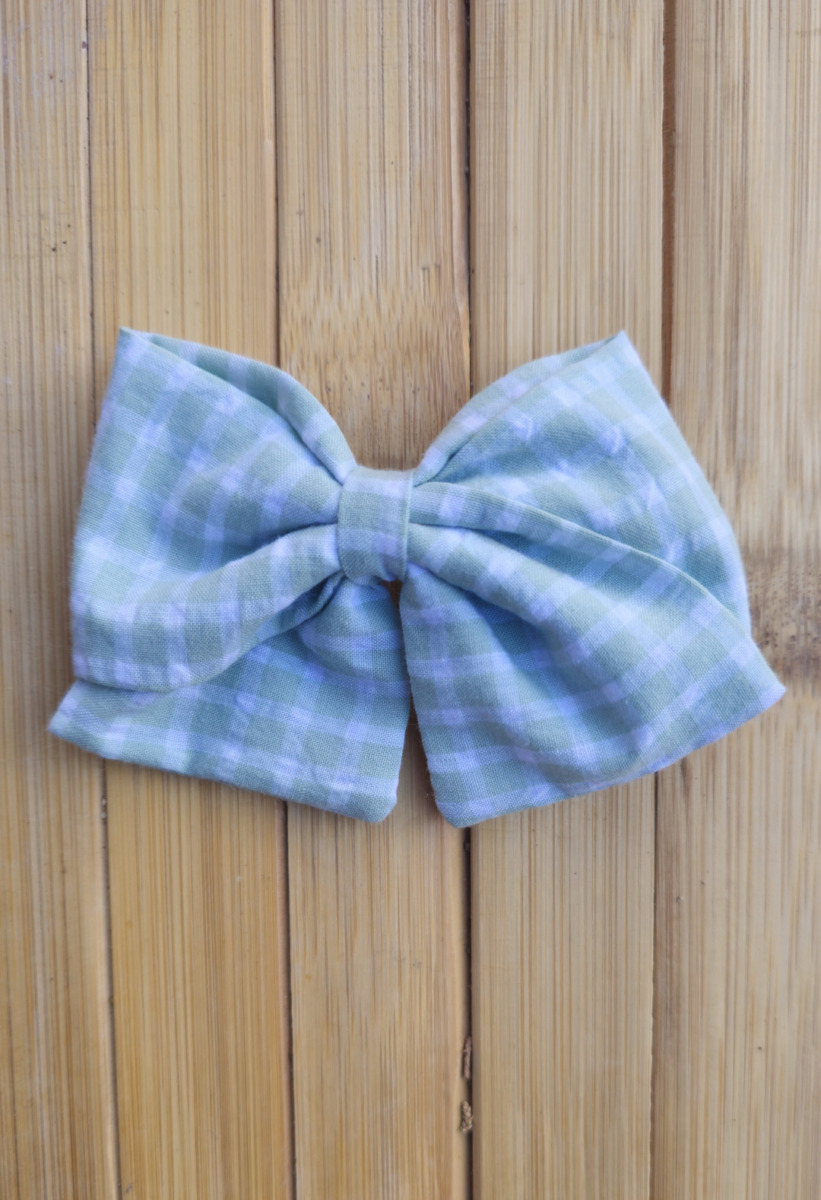 Lazo infantil de tela vichy verde con cuadros blancos sobre fondo de madera.