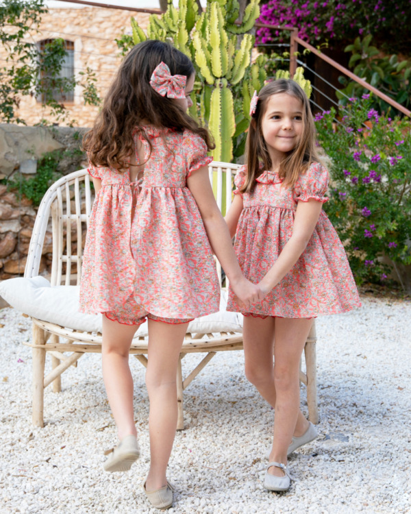 Dos niñas con vestidos florales a juego en tonos coral - Moda infantil artesanal para hermanas | Sutier