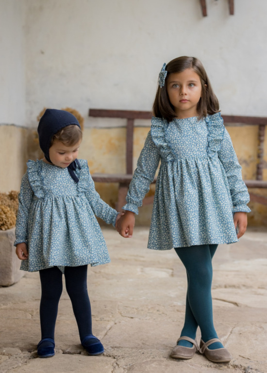 Hermanas combinando vestidos de la colección Asón de Sutier, con estampado floral azul y detalles delicados, ideales para ocasiones especiales.