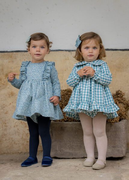 Dos bebés luciendo jesusitos de las colecciones Asón y Sella de Sutier, combinando estampado floral y cuadros vichy azafata con un estilo encantador.