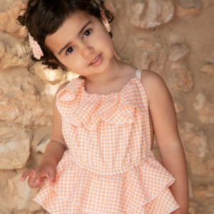 Conjunto infantil con volantes y estampado vichy melocotón, detalle de lazo en el cabello.