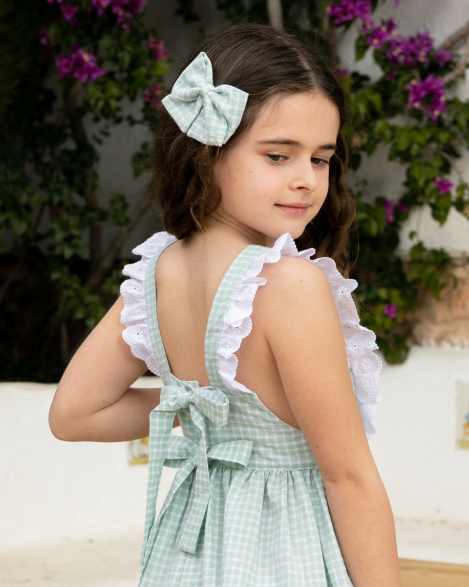 Niña con vestido verde a cuadros con volantes blancos y lazo en la espalda, colección de moda infantil Sutier.