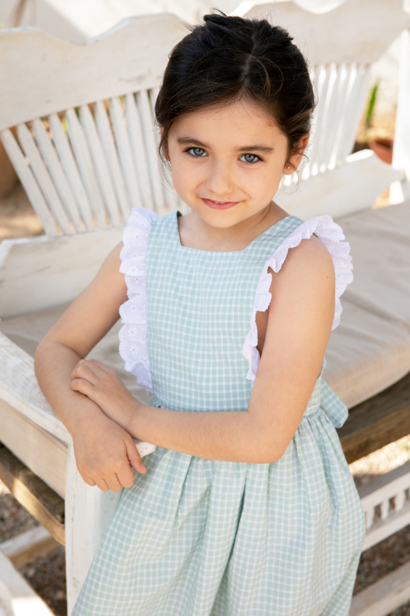 Niña con vestido verde a cuadros con volantes blancos, colección de moda infantil Sutier.