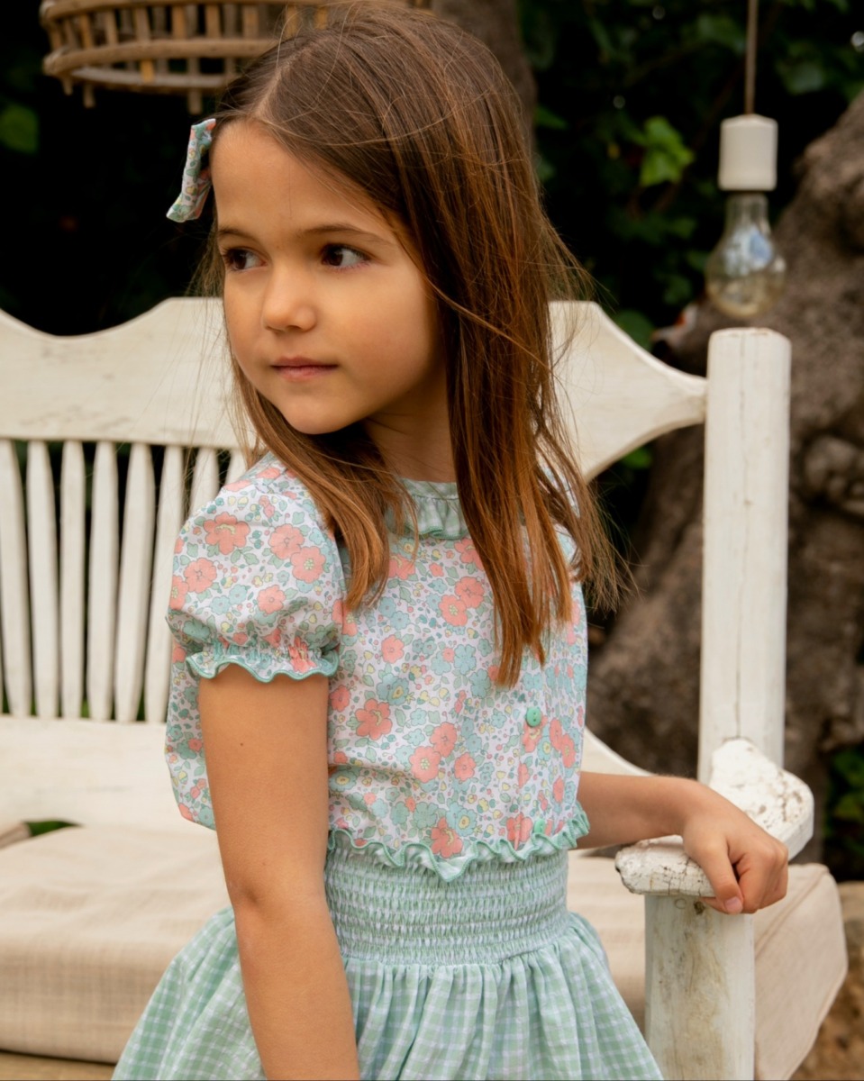 Niña con conjunto infantil compuesto por blusa floral y falda de cuadros vichy verde, estilo artesanal y veraniego