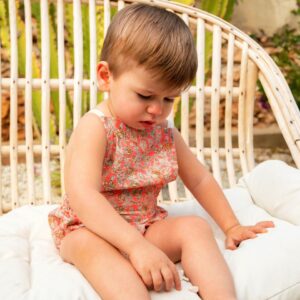 Niño sentado con ranita floral en tonos coral, moda infantil artesanal con estilo veraniego