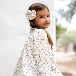 Niña con vestido floral blanco y lazo a juego en el pelo, moda infantil Sutier