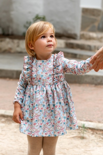 Niña pequeña con vestido infantil de manga larga y volantes, estampado floral rosa y azul de Sutier