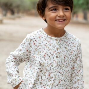 Niño sonriente con blusa floral blanca de manga larga, moda infantil Sutier
