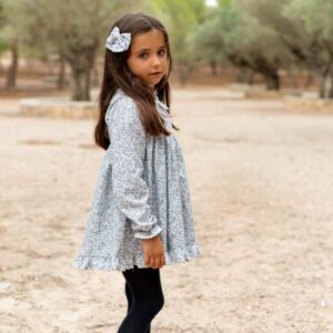 Niña con vestido infantil azul floral de Sutier y lazo a juego en el cabello