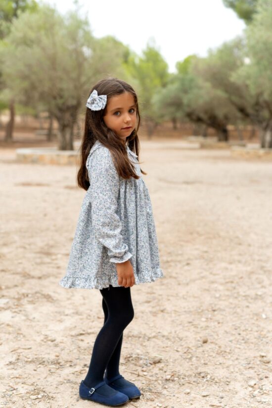 Niña con vestido infantil azul floral de Sutier y lazo a juego en el cabello