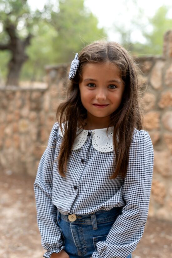 Blusa Nogal de niña en cuadros vichy azul y blanco con cuello bordado. Moda infantil artesanal hecha en España, cómoda, versátil y elegante para cualquier ocasión.