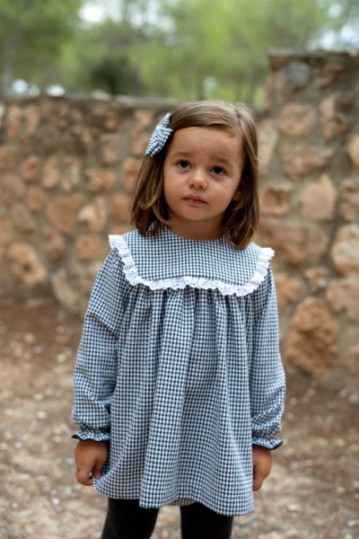 Niña con vestido infantil de cuadros vichy en blanco y negro con cuello volante y lazo a juego de Sutier