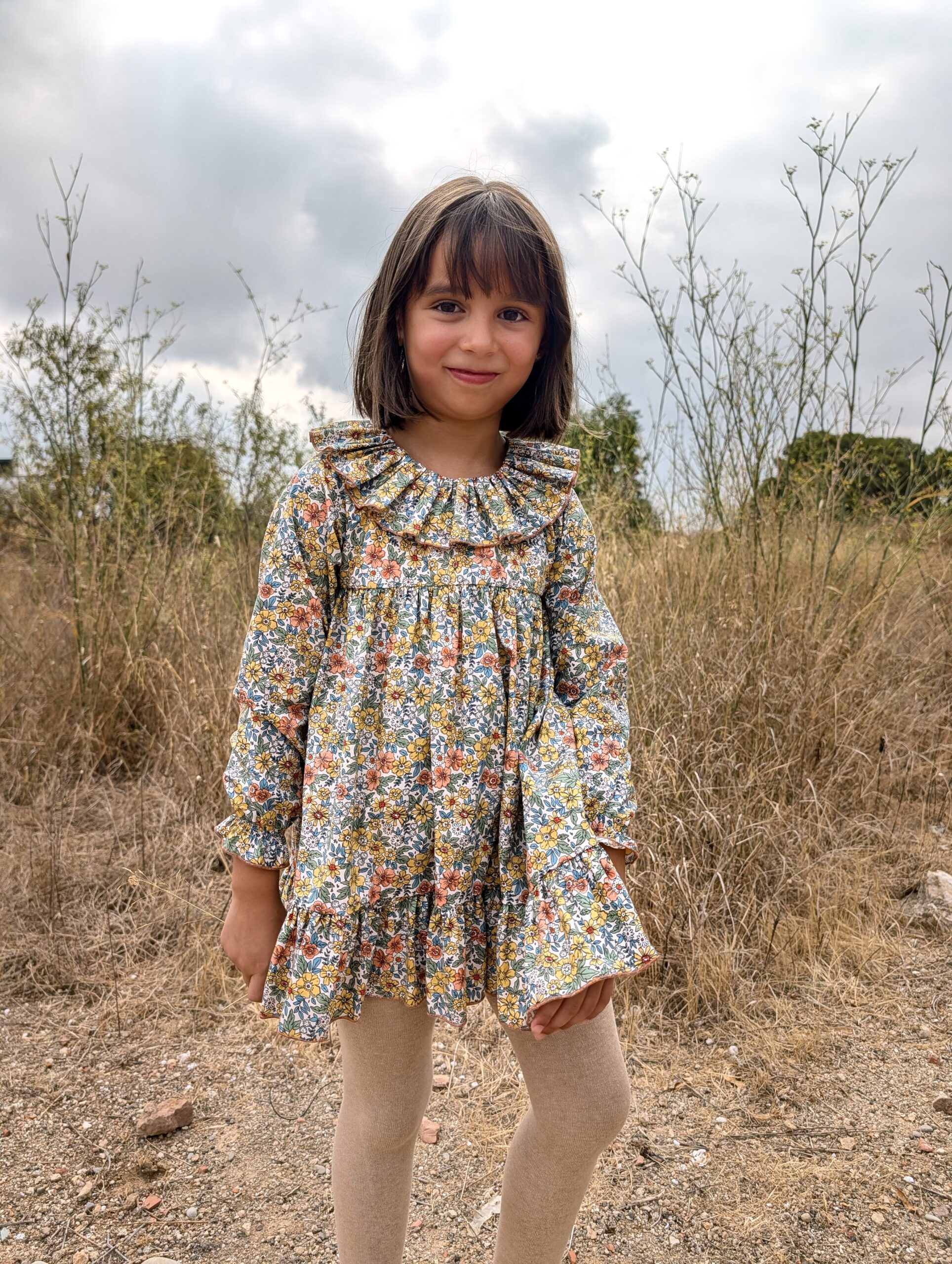 Vestido de niña con estampado floral en tonos mostaza, rosa y azul, colección Evelyne